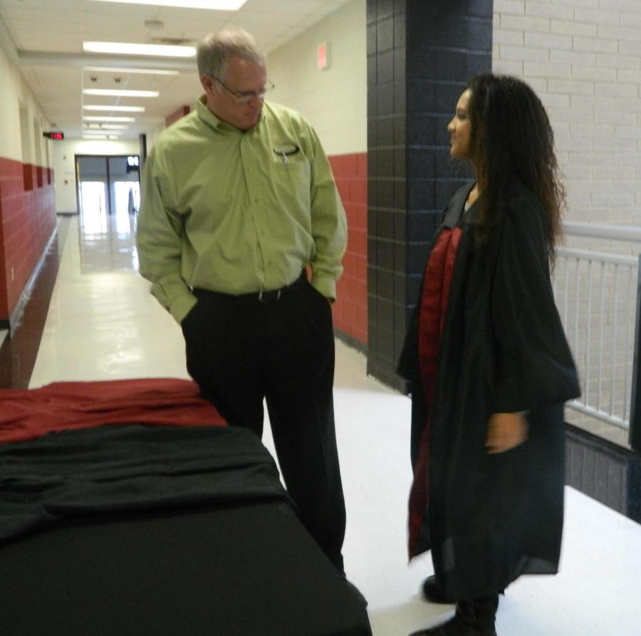 Harlan County High School senior Sierra Hatfield talked with Dave Gash of Jostens as she tried on a graduation gown. Seniors are making their choices as they prepare for graduation in May.
