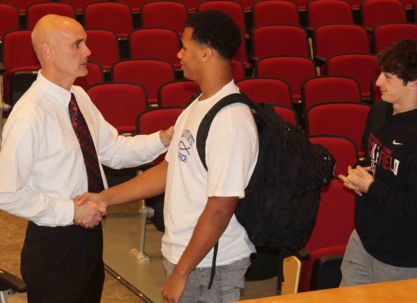 Harlan County coach Jacob Saylor talked with Shemar Carr and Gage Bailey after a meeting at the schools auditorium.